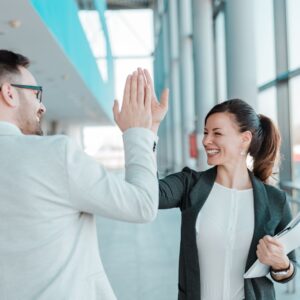 Man and woman giving each other a high five in the office